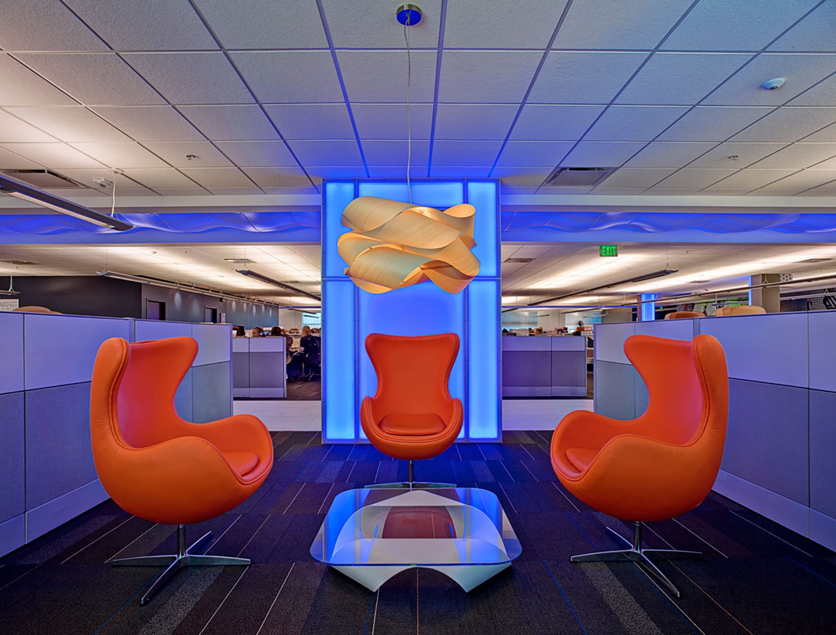 North American Bancard Headquarters flexible conference space with backlit feature wall, bold orange chairs, and a decorative chandelier