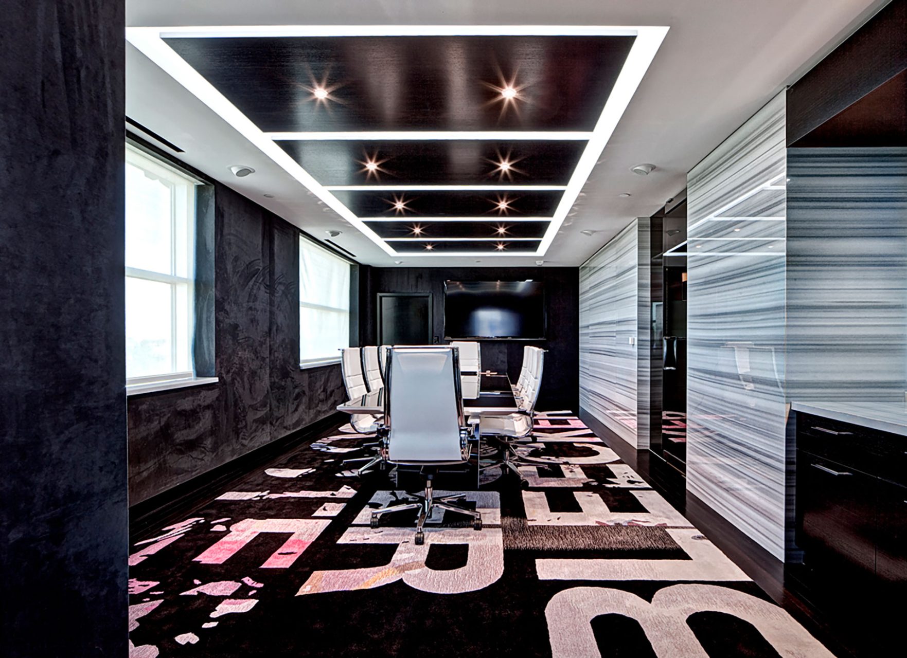 modern style conference room with large bold text carpet design, black ceiling tiles, and slab tile wall covering