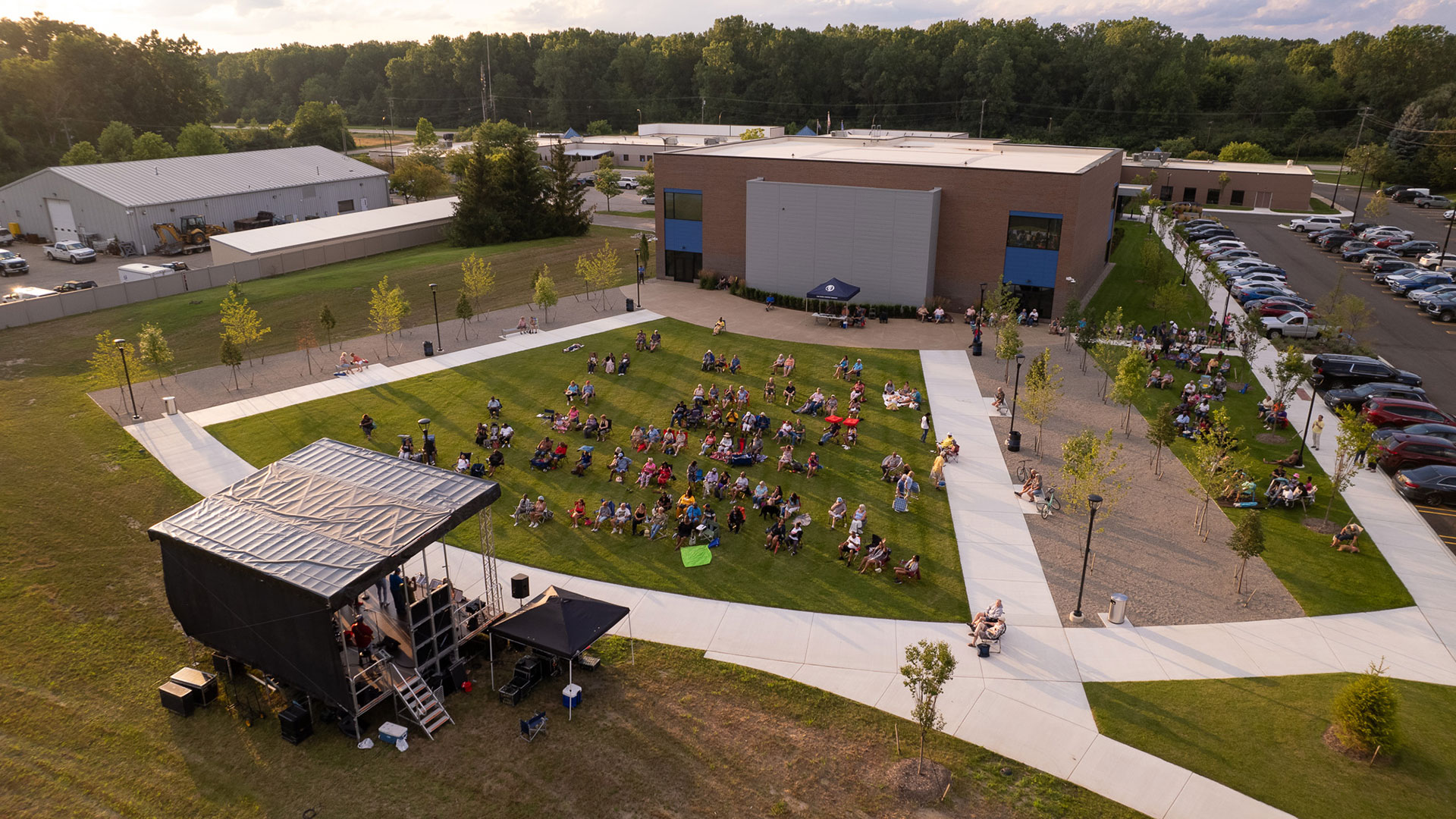 van buren community center aerial view of outdoor event. people are sitting in the park listening to music on a summer night.