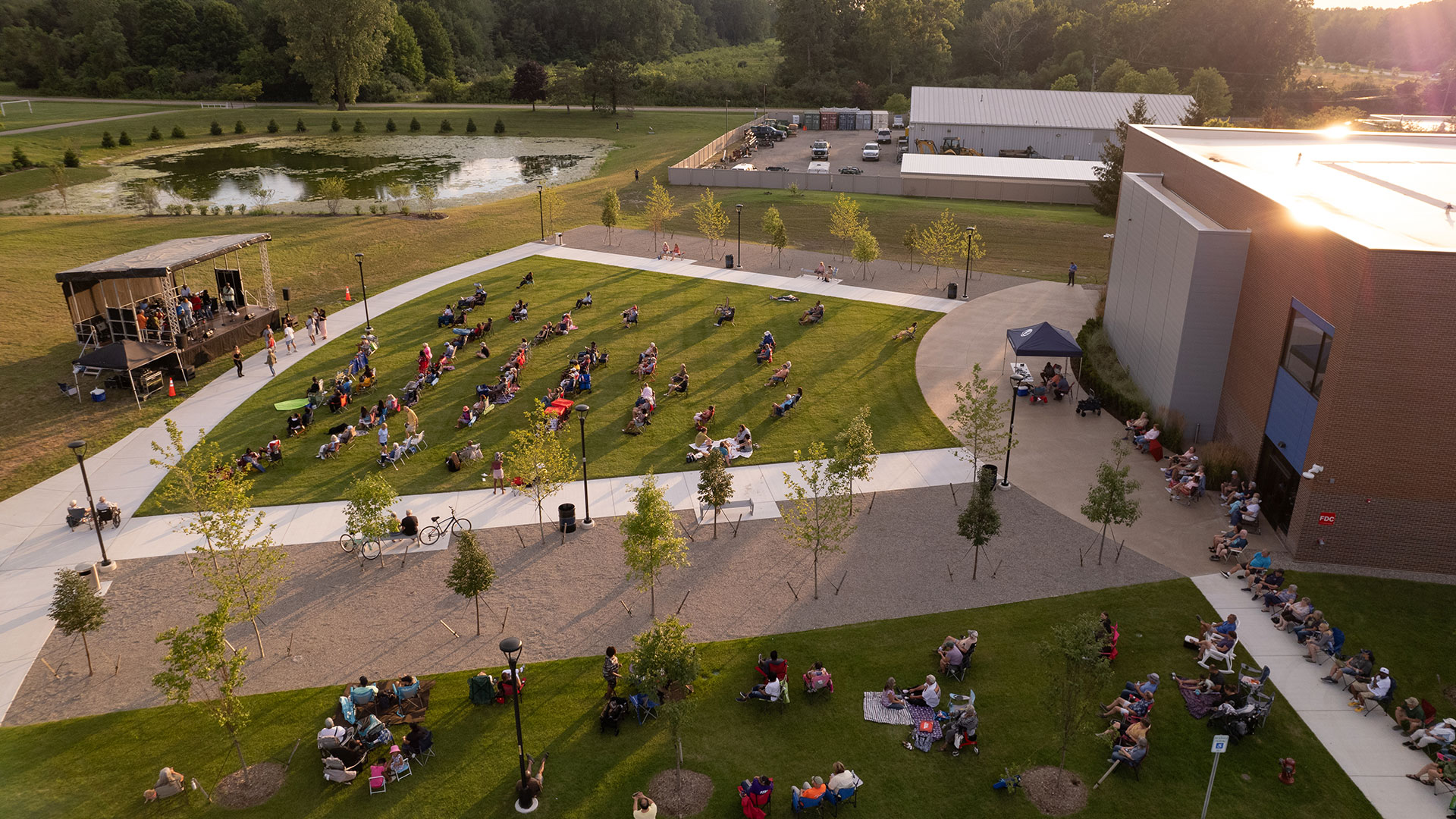 van buren community center aerial view of outdoor event. people are sitting in the park listening to music on a summer night.