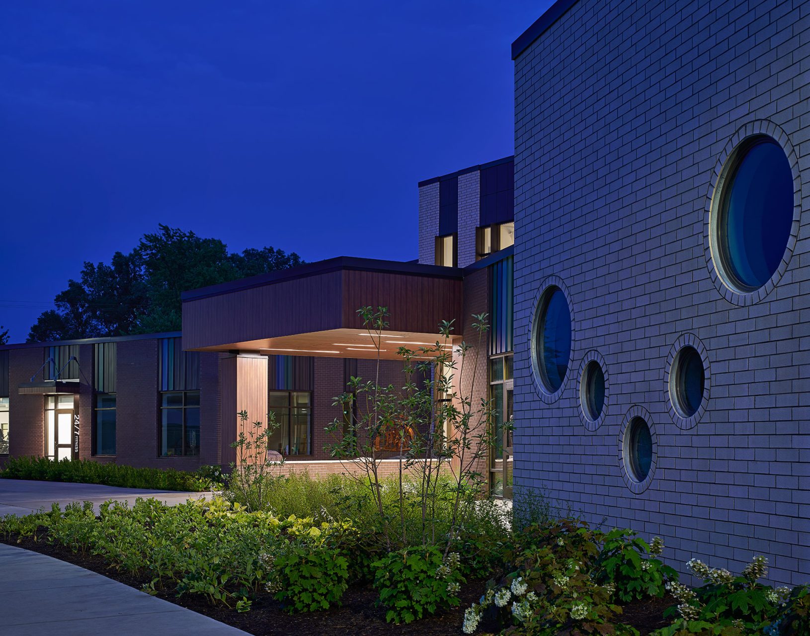 exterior at dusk with landscaping, up lighting, and circular windows